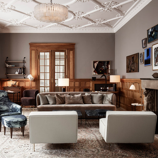 Elegant living room with neutral gray walls, plush gray and cream furniture, and ornate patterned carpet.
