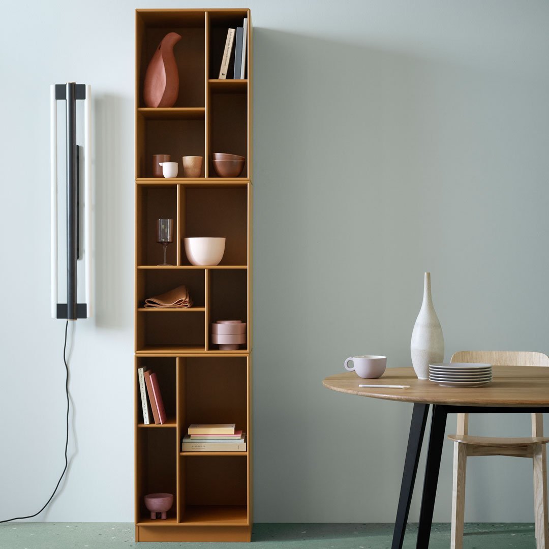 Sleek wooden shelf in warm brown with pastel pink and white decor items against a soft green wall. Modern minimalist design.