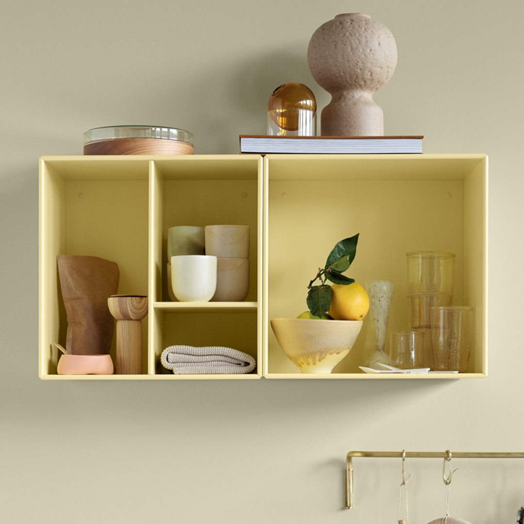 Yellow cubby shelves with assorted glassware, ceramics, and decorative items on a soft, neutral background.