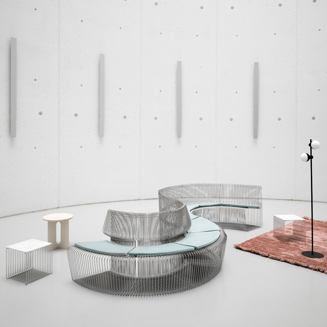 Modern curved indoor seating in silver and teal, complemented by a rust-colored rug and sleek geometric tables.