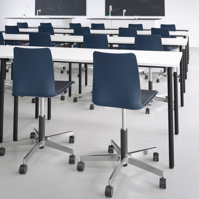 Navy blue ergonomic chairs with chrome bases and white tabletops in a modern classroom setting.