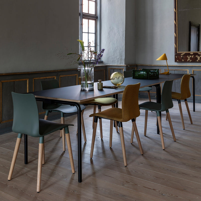 Stylish dining table with dark surface, paired with green and brown chairs, showcasing a modern, minimalist aesthetic.