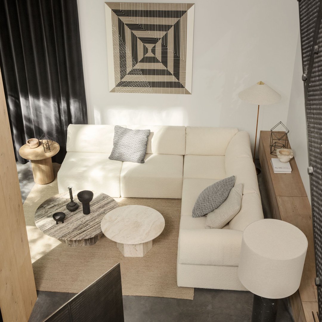 Modern cream sectional sofa with geometric-patterned throw pillows and a black and white accent wall.