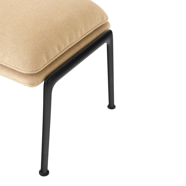 Beige cushion with smooth texture atop a sleek black metal frame. Minimalist design for modern interiors.