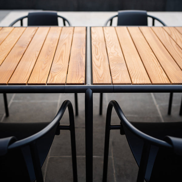 Modern wooden table with sleek black chairs, featuring natural wood grain and smooth, linear patterns.