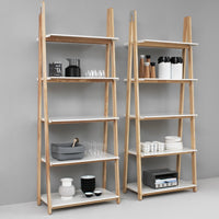 Two wooden shelving units with white shelves and minimalist design, featuring a mix of glass and ceramic items.
