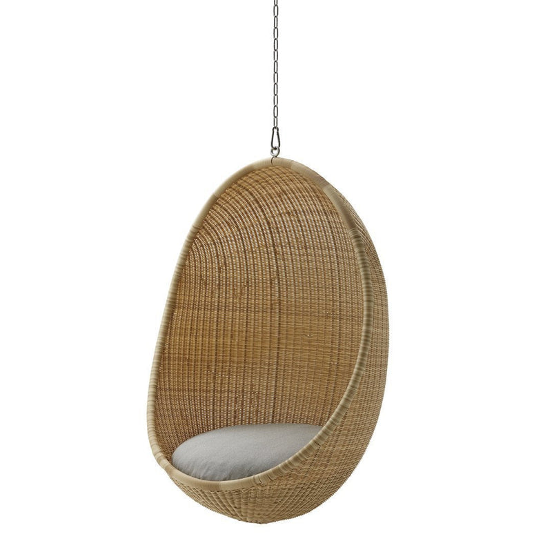 Hanging egg-shaped chair in natural wicker with a soft gray cushion. Elegant, minimalist design and warm tones.