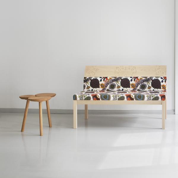 Patterned bench featuring vibrant floral and abstract designs in earthy tones, paired with a minimalist wooden table.