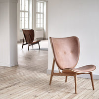 Copper-toned leather chair with a smooth, minimalist design and subtle tufted pattern, set against a light wooden floor.