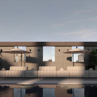 Modern outdoor lounge with neutral beige couches, gray walls, and beige umbrellas reflecting sunlight over the pool.