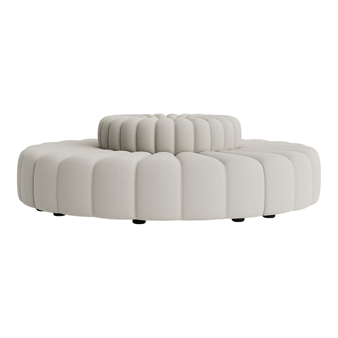 Cream-colored circular ottoman with tufted ribbed pattern and smooth, rounded edges. Ideal for modern decor.