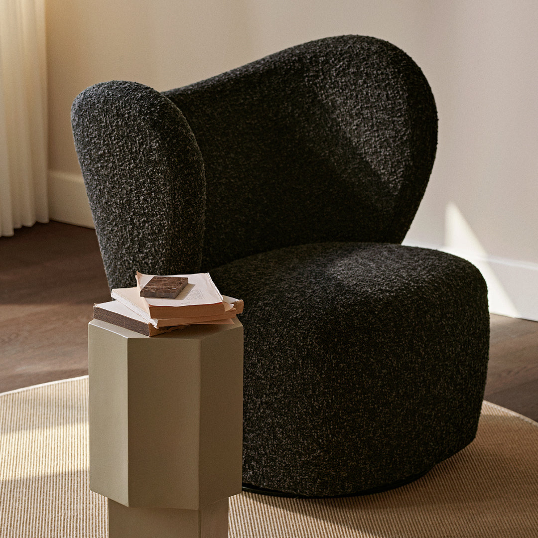 Textured black upholstery armchair with a unique curved design, paired with a minimalist light-colored side table.
