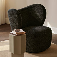 Textured black upholstery armchair with a unique curved design, paired with a minimalist light-colored side table.