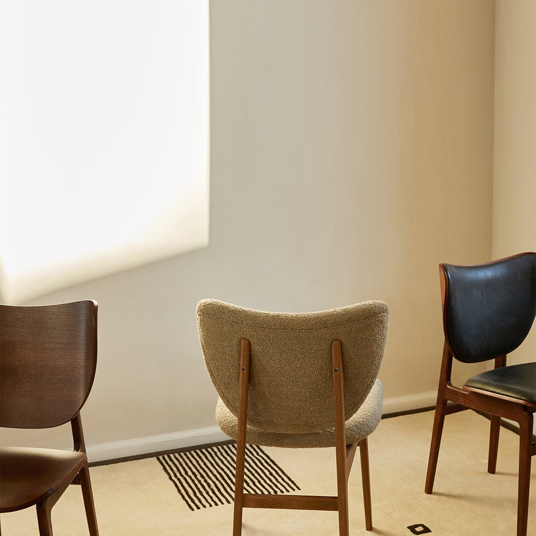 Three stylish chairs in earthy tones: wood, beige, and dark blue, showcasing a modern, minimalist design.