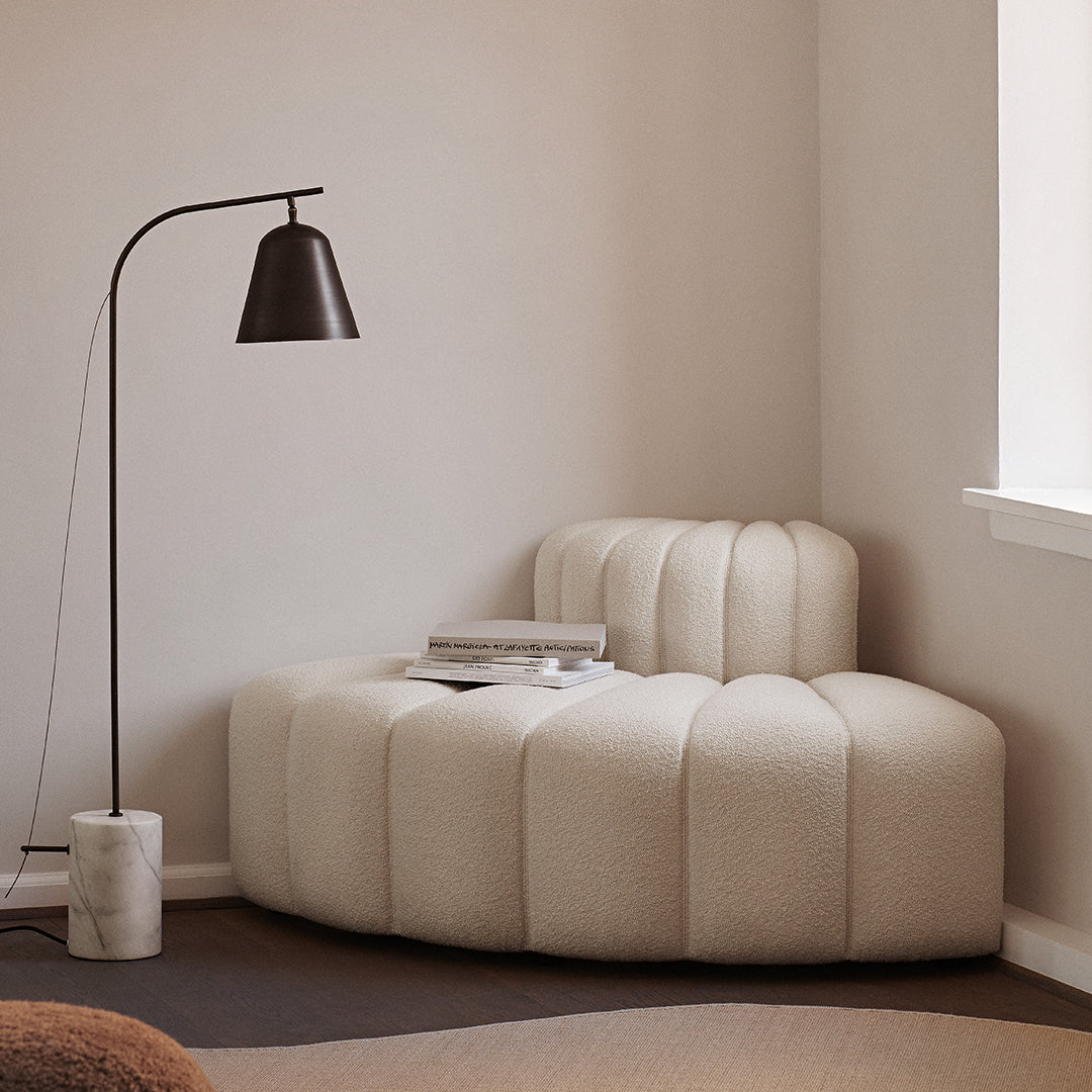 Curved cream sofa with quilted texture, complemented by warm brown tones and minimalistic decor.