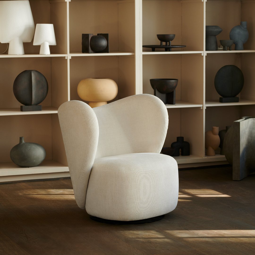 Cream-colored accent chair with a sculptural design, featuring soft curves and a plush texture, perfect for modern interiors.