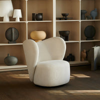 Cream-colored accent chair with a sculptural design, featuring soft curves and a plush texture, perfect for modern interiors.