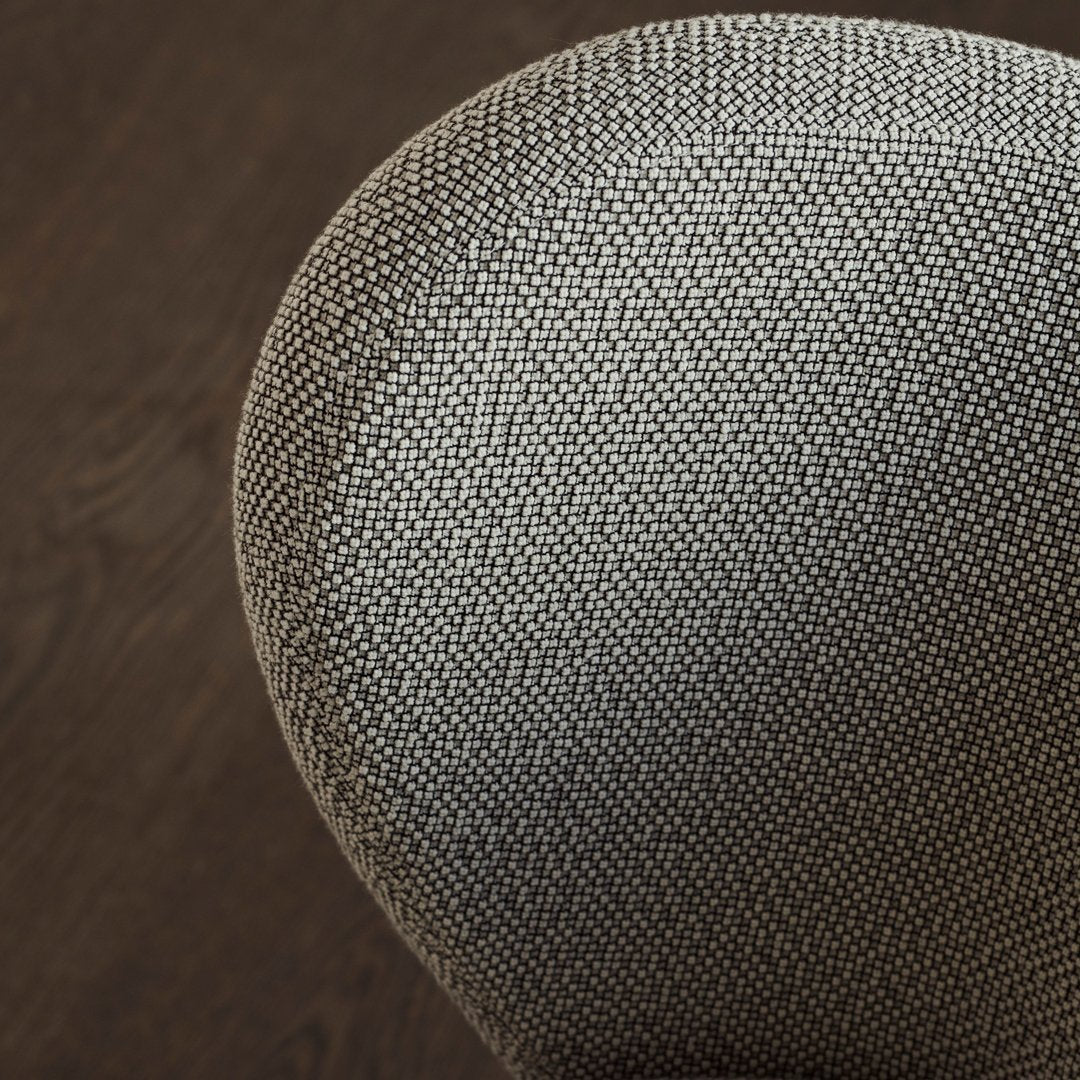 Textured gray upholstery pattern on a rounded chair surface, contrasting with a dark wooden floor.