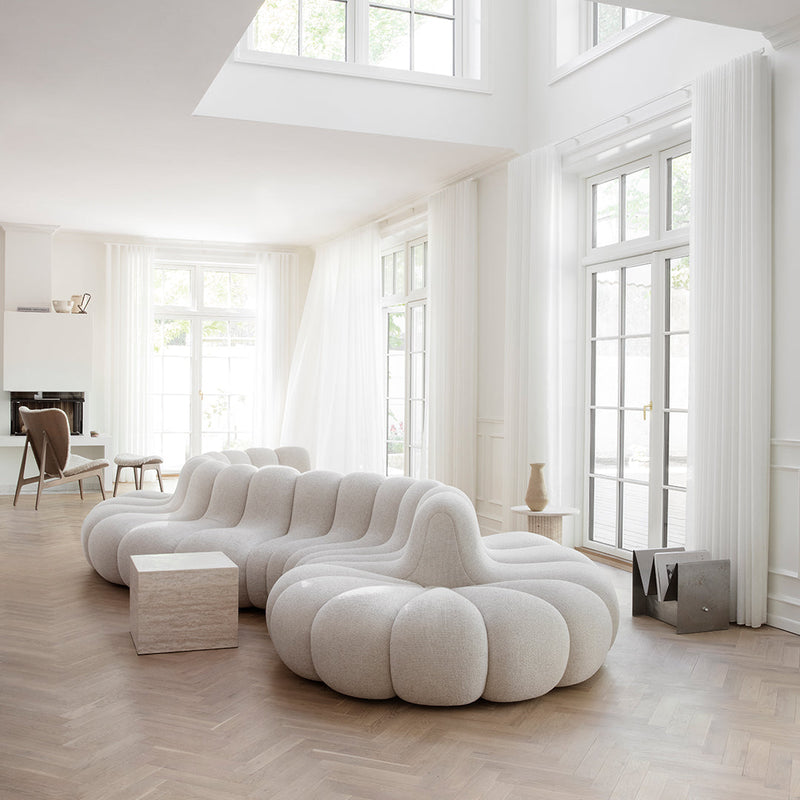 White tufted sofa with a smooth, rounded design in a bright, airy room featuring natural light and neutral tones.