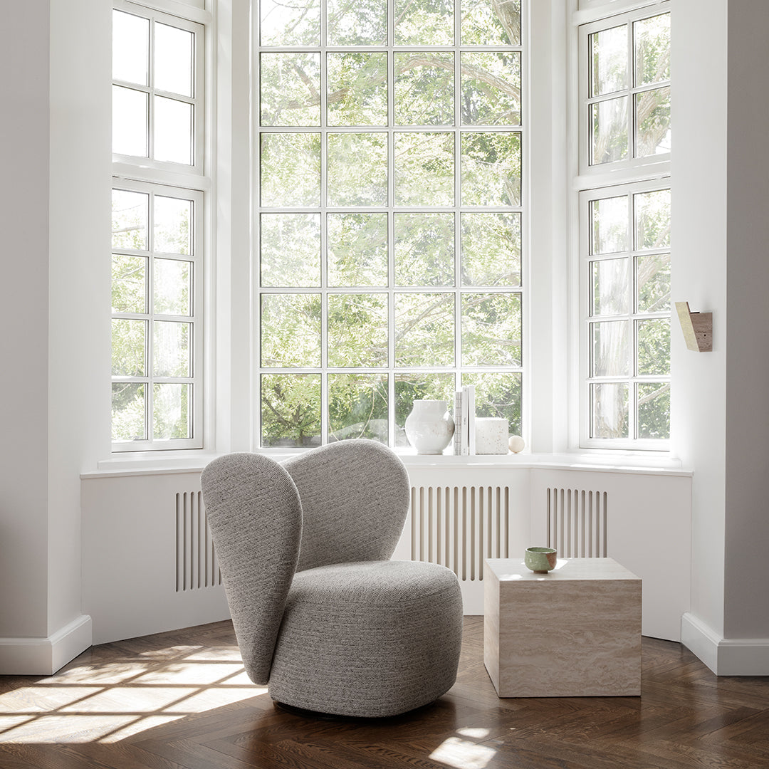 Gray upholstered chair with a sleek, modern design, positioned next to a light-colored square table in a bright setting.