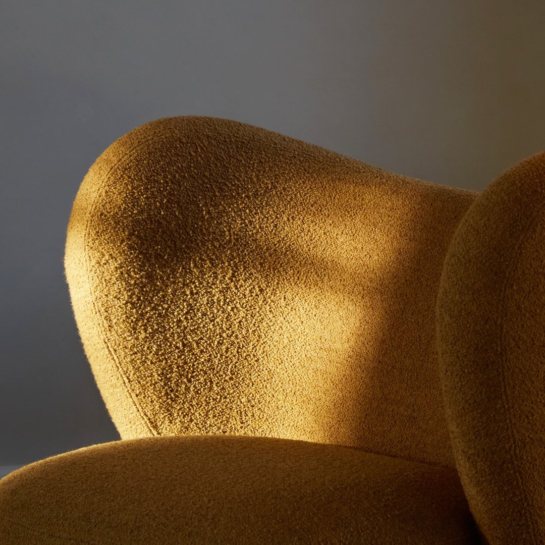 Soft, textured golden upholstery on a modern sofa arm, highlighting warm tones and gentle curves.