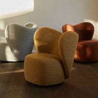Stylish armchair in mustard yellow, with a smooth, sculptural shape; a backdrop of soft gray, orange, and beige chairs.