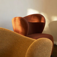"Textured orange and brown lounge chairs with smooth curves, set against a neutral backdrop."