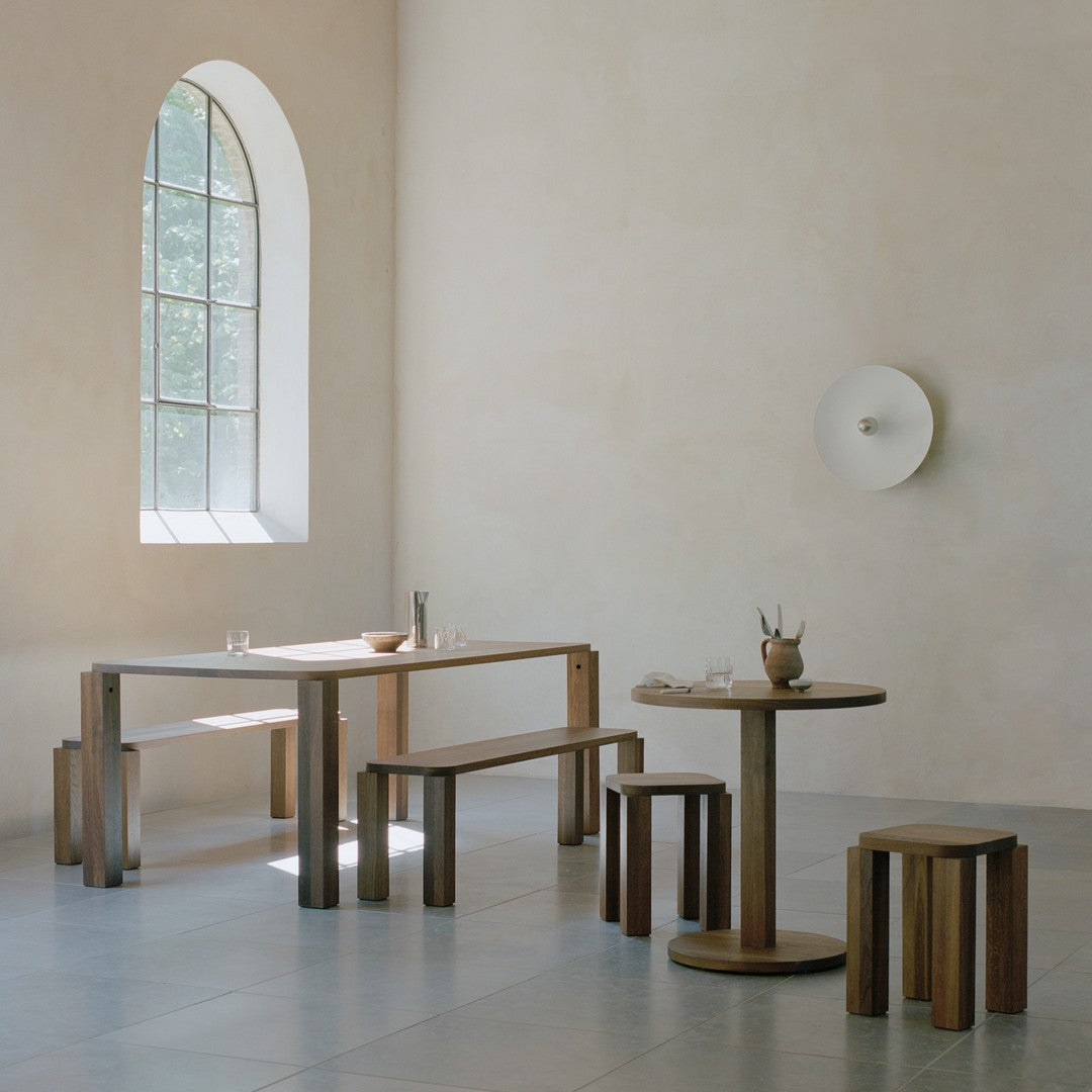Warm wood tones with smooth finishes; simple, modern shapes against light beige walls and grey tiles.