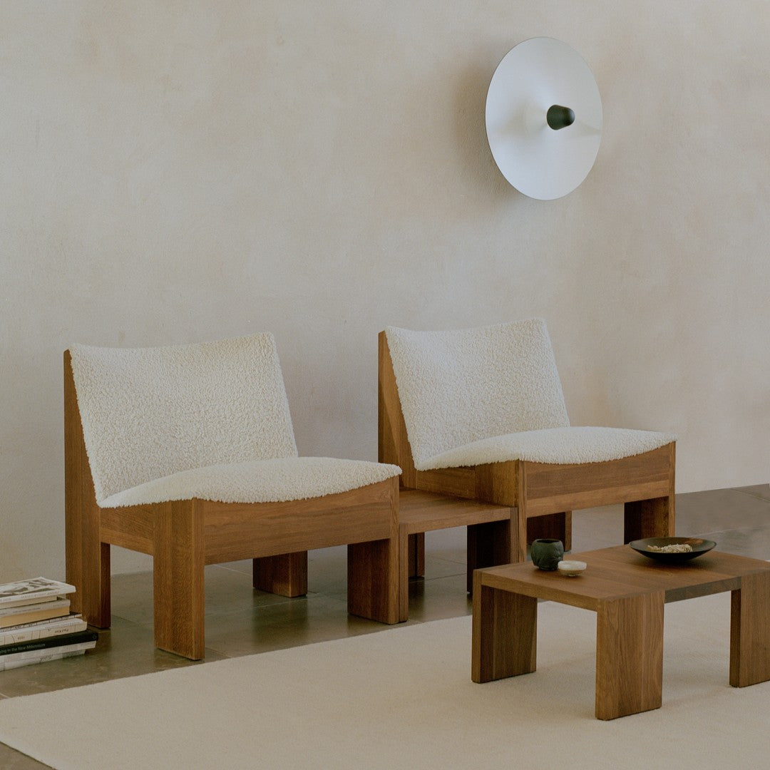 Cream upholstered lounge chairs with natural wood frames in a minimalistic setting. Soft textures and neutral tones.