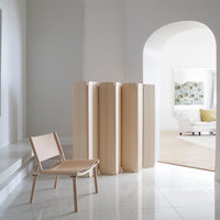 Modern room divider in a minimalistic interior setting with a chair and sofa.