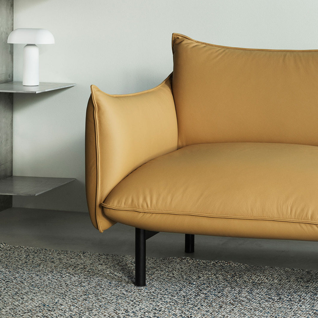 Stylish mustard yellow sofa with plush cushions and minimalist black legs, set against a neutral background.