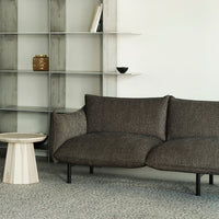 Curved brown sofa with a textured fabric, set against a minimalist backdrop and light-colored furniture.