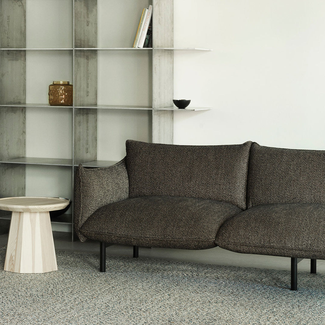 Curved brown sofa with a textured fabric, set against a minimalist backdrop and light-colored furniture.