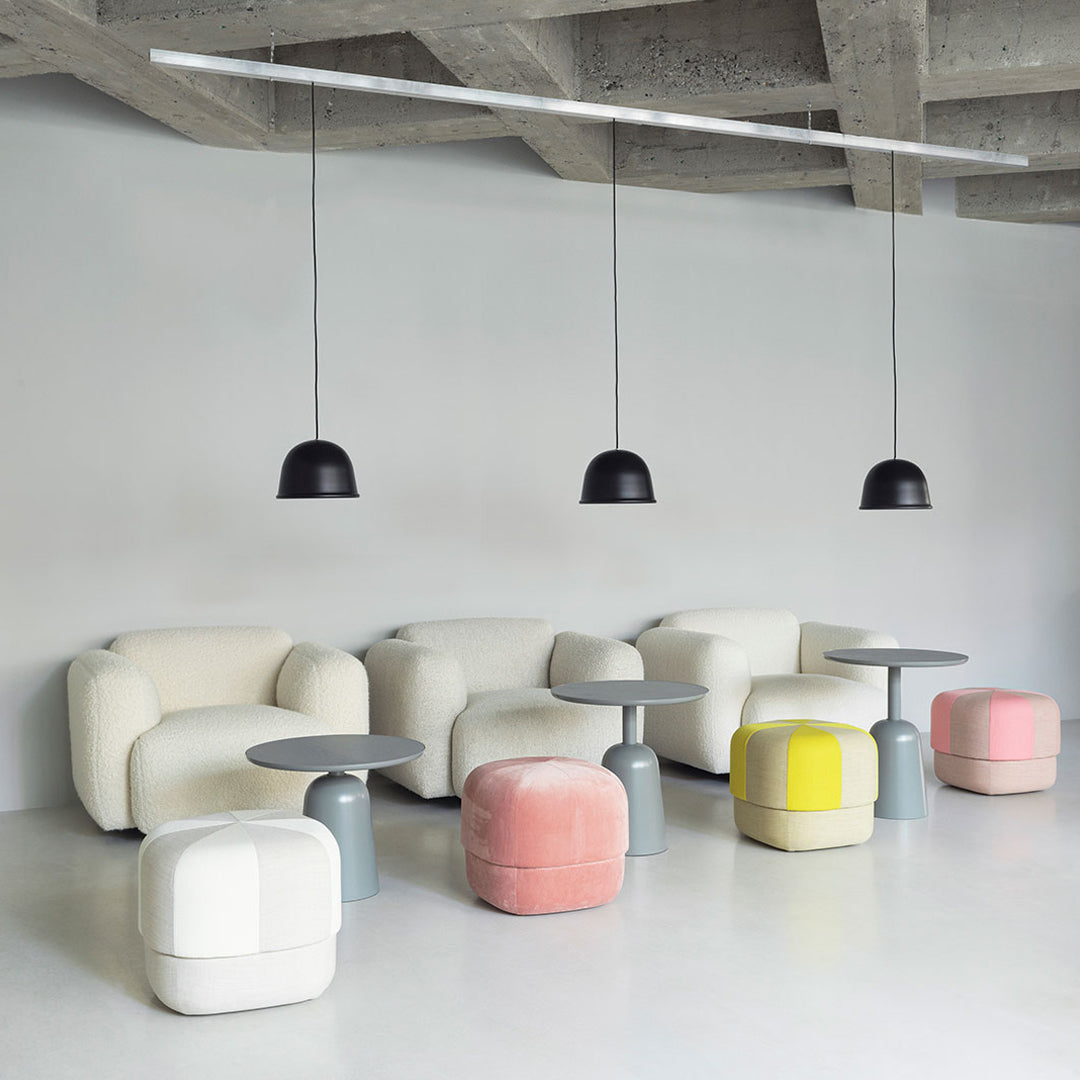 Modern lounge area featuring white sofas, gray tables, and colorful poufs in yellow, pink, and pastel hues.