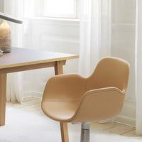 Tan modern chair with a smooth, curved design, set against a light, airy room with soft natural lighting.