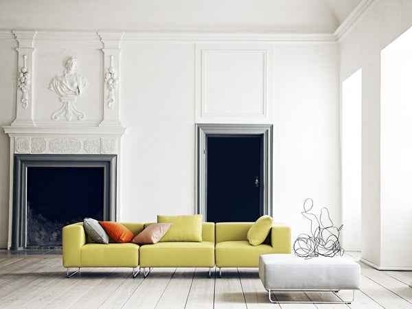 Bright yellow sofa with colorful accent pillows against a minimalist white interior. Modern design with clean lines.