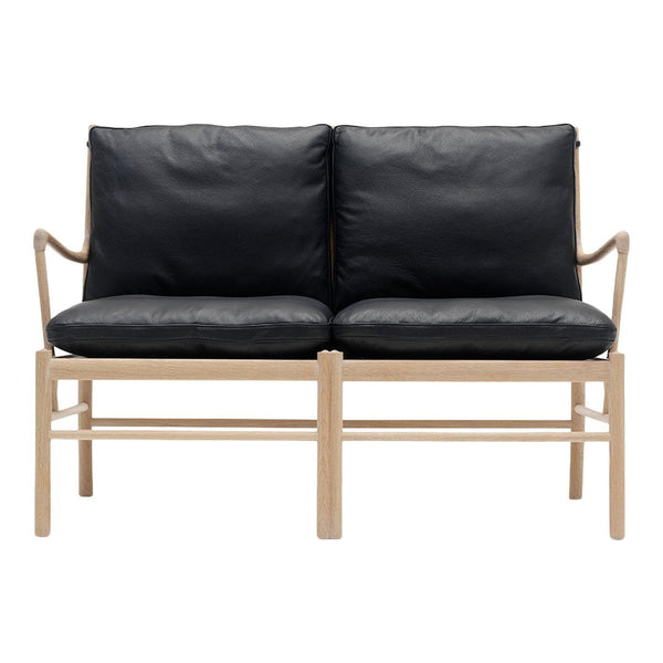 Black leather loveseat with a light wood frame, featuring a modern, minimalist design and sleek lines.