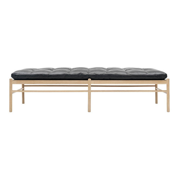 Black tufted cushion on a natural wood frame, featuring simple lines and a modern design. Ideal for contemporary spaces.