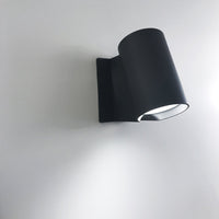 Sleek black wall lamp with a minimalist design, featuring a smooth matte finish and a cylindrical shade.
