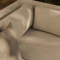 Beige and light gray sofa with a textured throw pillow, featuring a minimalistic and modern design.