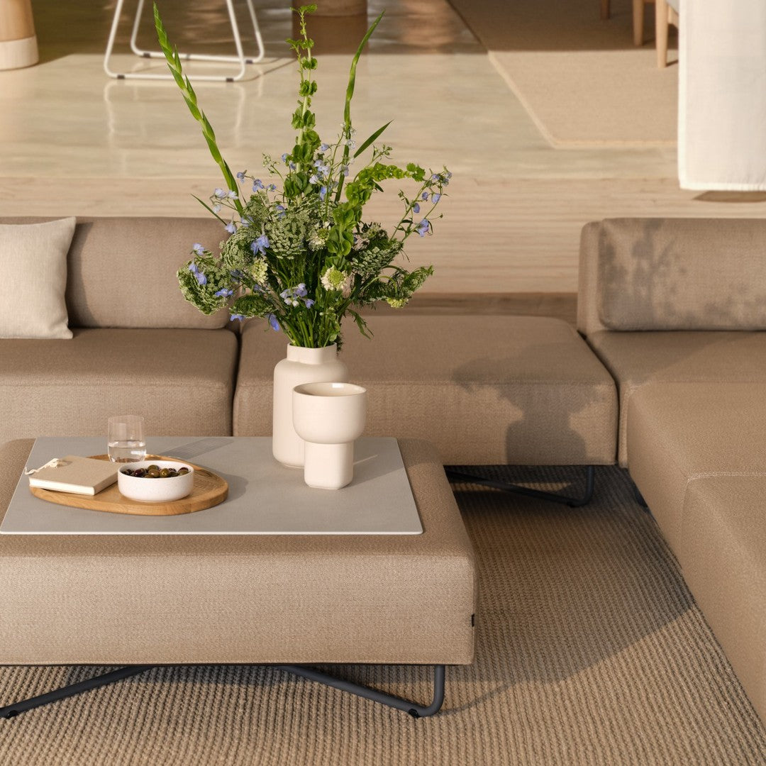 Beige sectional sofa with textured cushions, paired with a minimalist light-gray coffee table and neutral area rug.