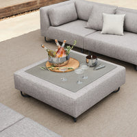 Gray fabric sectional sofa with a sleek square coffee table, featuring a subtle pattern and a glass top. Elegant and modern design.