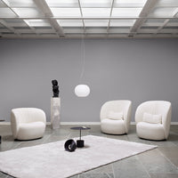 Elegant white chairs on a soft, textured gray rug against a neutral gray wall, complemented by a minimalist pendant light.