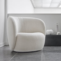 Cream-colored, plush chair featuring subtle vertical ridges, set against a minimalistic, modern interior.