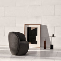 Textured dark gray chair against a minimalist light wall, complemented by abstract black and beige artwork.