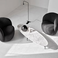 Modern black upholstered armchairs with a minimalist gray marble coffee table in a bright, spacious setting.