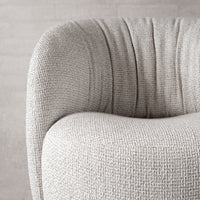 Textured light gray upholstery with soft pleats, showcasing a modern, cozy design aesthetic.