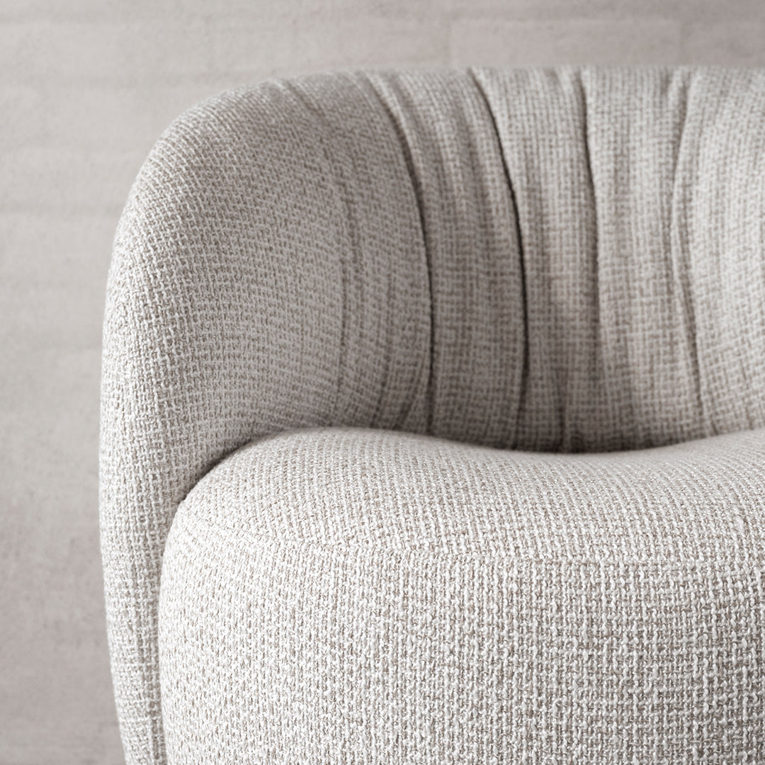 Textured light gray upholstery with soft pleats, showcasing a modern, cozy design aesthetic.