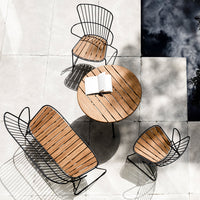 Wooden patio furniture set with black metal frames and slatted design, featuring a round table and two matching chairs.