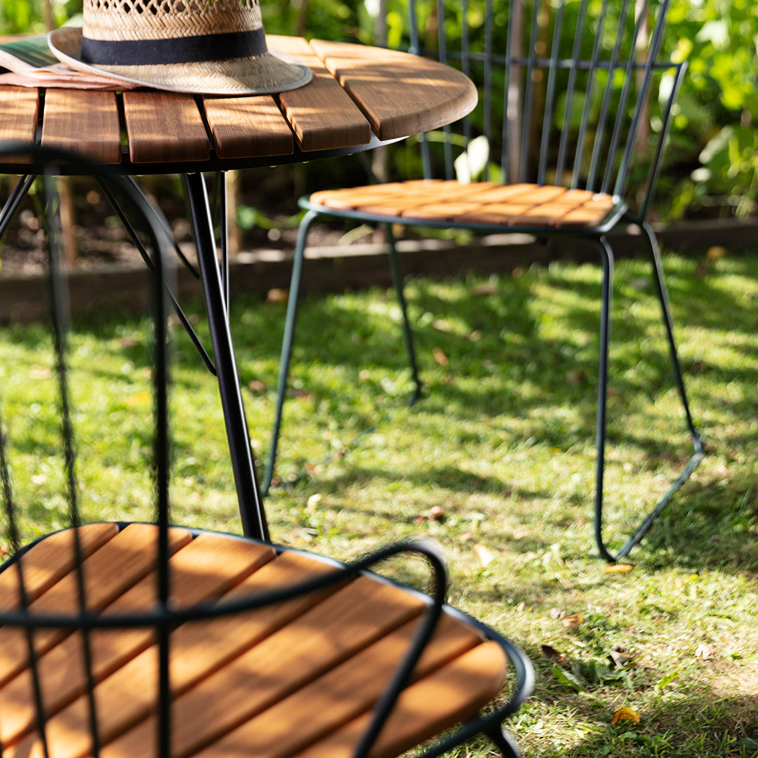 Stylish outdoor furniture set featuring a round wooden table with black metal legs and matching wood seat chairs.